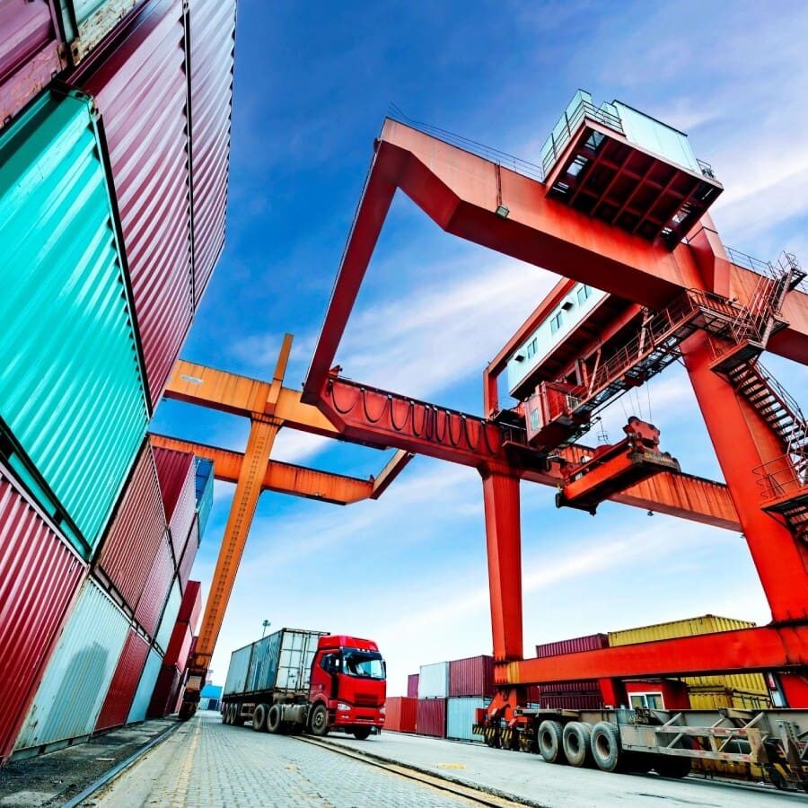 A red truck is parked next to some containers.